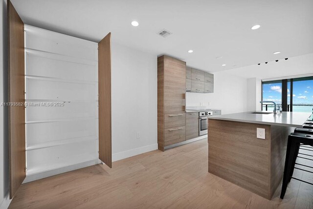 650 NE 32nd St Unit 1004, Miami, FL 33137 - kitchen featuring oven, a sink, light wood finished floors, light countertops, and modern cabinets