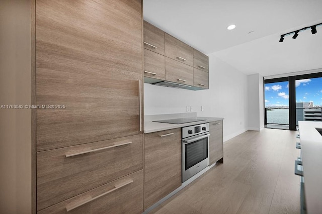 650 NE 32nd St Unit 1004, Miami, FL 33137 - kitchen with oven, black electric stovetop, baseboards, light wood-type flooring, and modern cabinets
