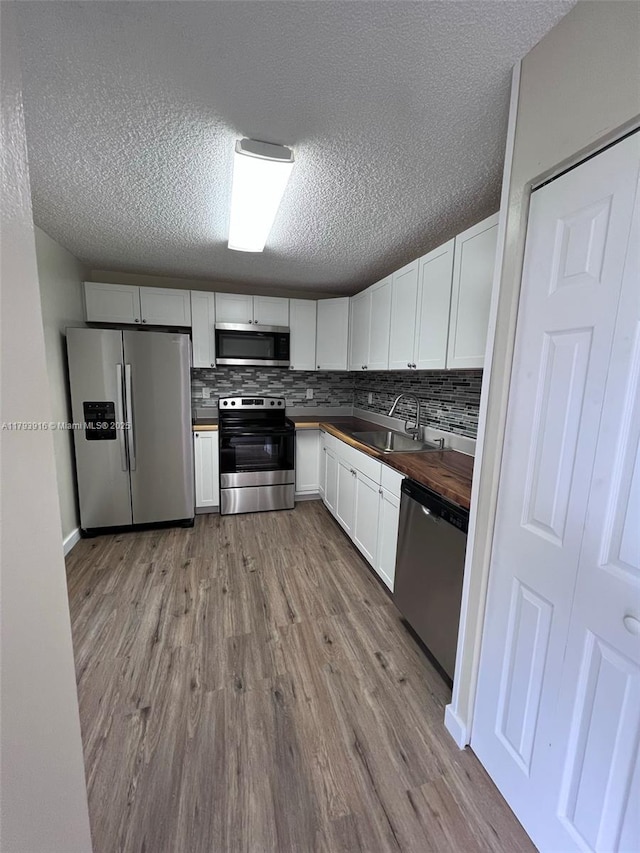 13776 SW 149 Circle Ln Unit 4-79, Miami, FL 33186 - kitchen featuring a textured ceiling, appliances with stainless steel finishes, wood finished floors, a sink, and wood counters
