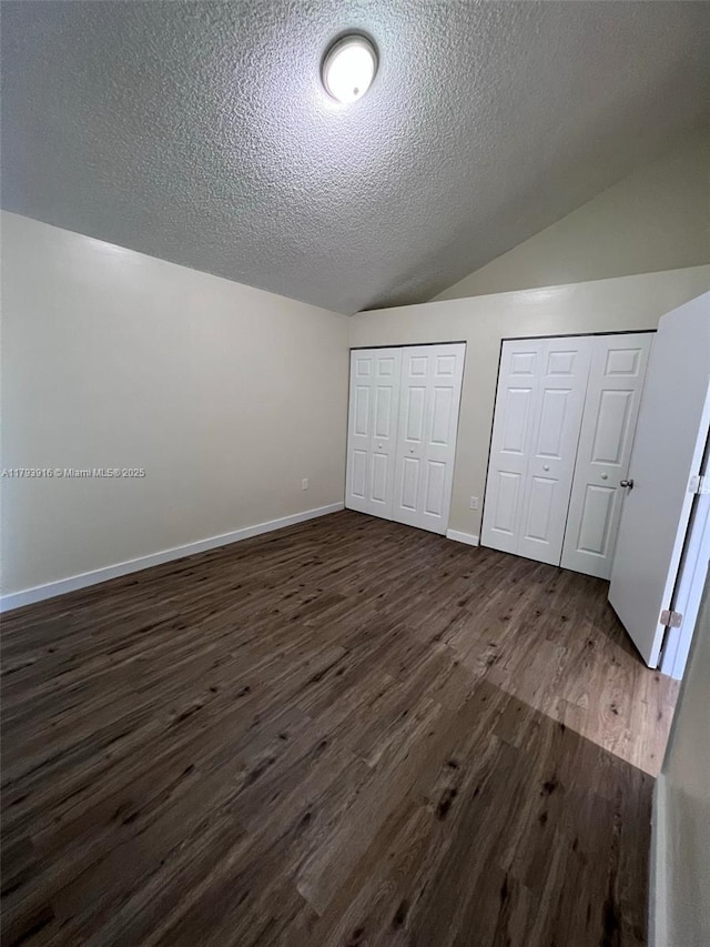 13776 SW 149 Circle Ln Unit 4-79, Miami, FL 33186 - unfurnished bedroom featuring dark wood-style flooring, a textured ceiling, and multiple closets