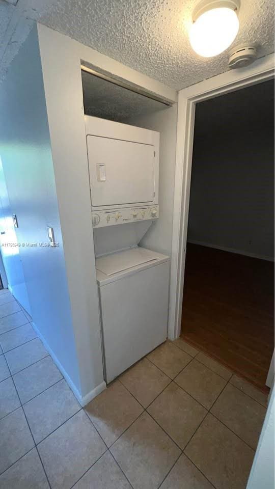 9044 NW 28th Dr Unit 3-202, Coral Springs, FL 33065 - washroom with stacked washing machine and dryer, light tile patterned floors, and a textured ceiling