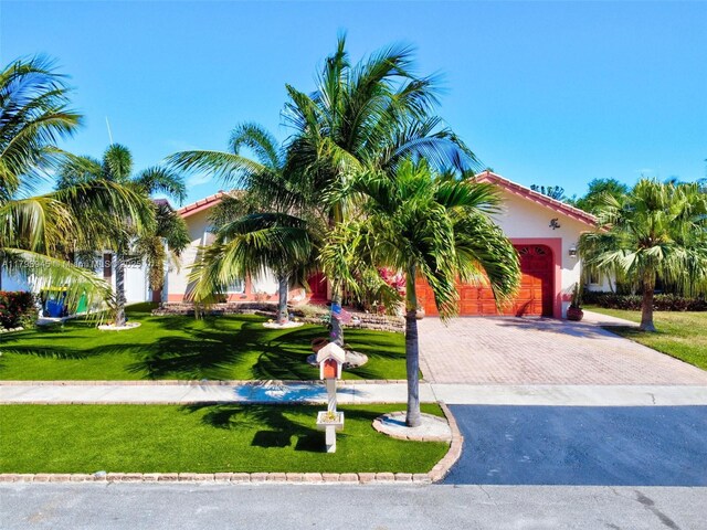 obstructed view of property featuring decorative driveway, a front lawn, and stucco siding