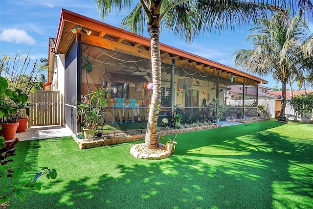 rear view of house featuring a lawn, ceiling fan, fence, and a gate