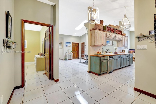 kitchen with baseboards, light countertops, a sink, and lofted ceiling with skylight