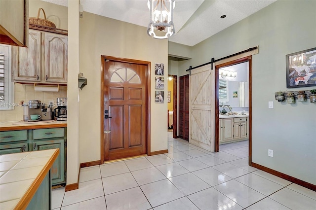 entryway with baseboards, a barn door, a textured ceiling, and light tile patterned floors