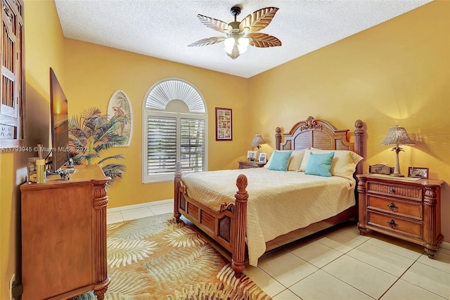bedroom with baseboards, a ceiling fan, a textured ceiling, and light tile patterned flooring