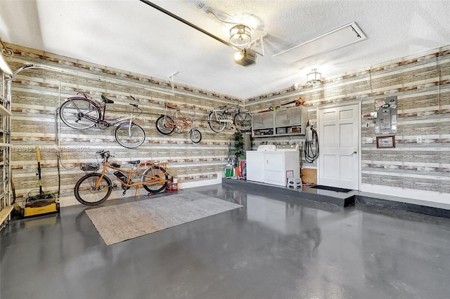 garage with washing machine and clothes dryer, baseboards, wood walls, and a garage door opener