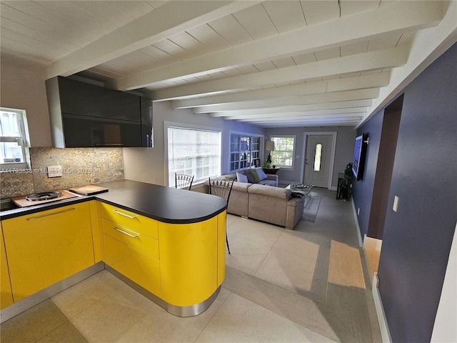 kitchen with dark countertops, a peninsula, open floor plan, tasteful backsplash, and beamed ceiling