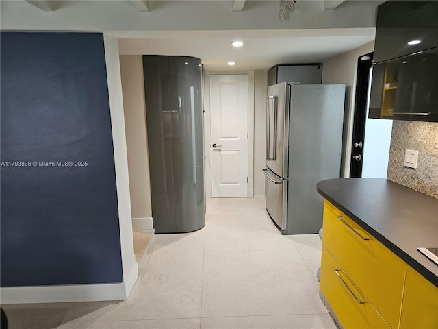 kitchen with dark countertops, freestanding refrigerator, recessed lighting, baseboards, and backsplash