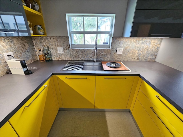 kitchen featuring backsplash, open shelves, a sink, and yellow cabinets