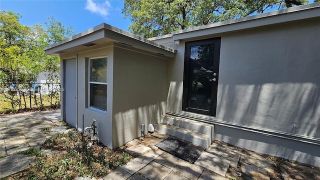 view of property exterior featuring stucco siding, fence, and entry steps