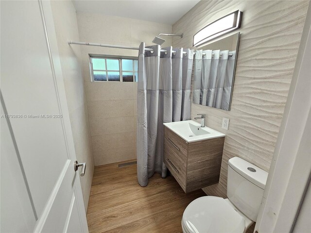 12120 NE 11th Pl, North Miami, FL 33161 - full bathroom with vanity, wood finished floors, toilet, tile walls, and tiled shower