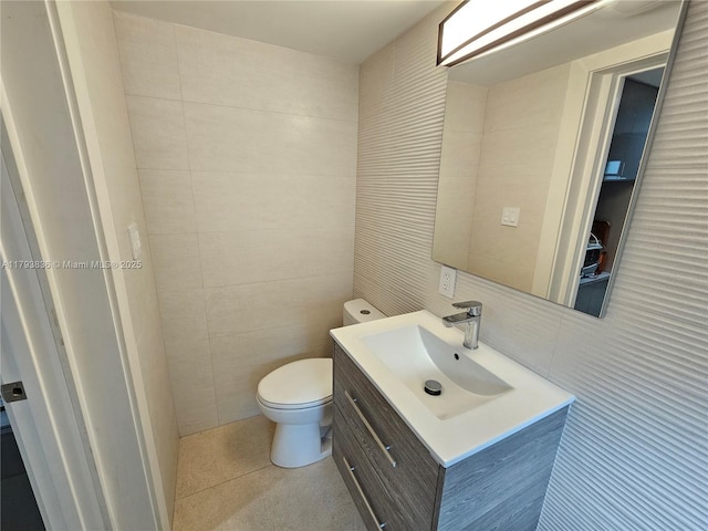 half bath featuring vanity, toilet, and tile walls