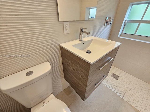 bathroom with vanity, toilet, and tile walls