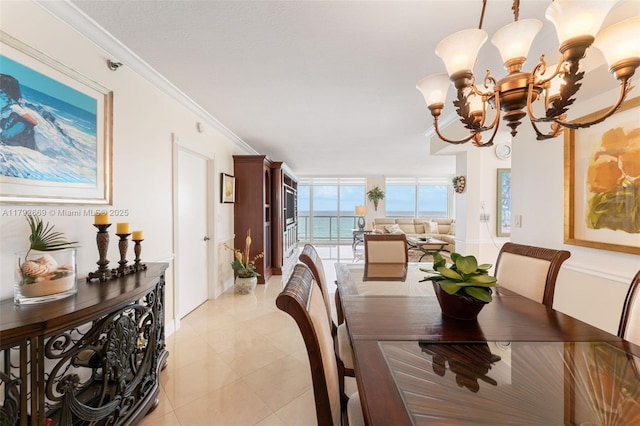 dining room with a notable chandelier, baseboards, light tile patterned floors, a water view, and ornamental molding