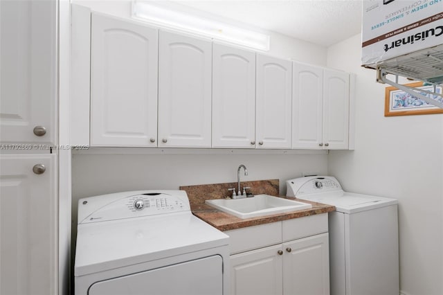 laundry room featuring a sink, a textured ceiling, independent washer and dryer, and cabinet space