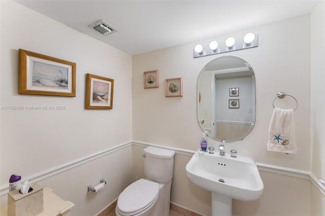 half bath featuring a sink, toilet, and visible vents