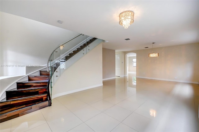 unfurnished living room with visible vents, stairs, baseboards, tile patterned floors, and arched walkways