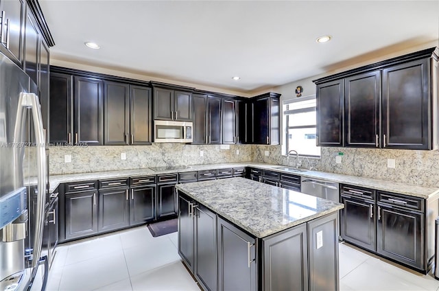 kitchen featuring a center island, tasteful backsplash, light stone countertops, a sink, and stainless steel appliances