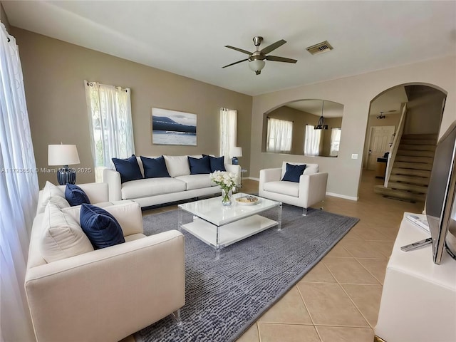 living room with visible vents, a ceiling fan, stairway, arched walkways, and light tile patterned floors