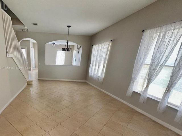 interior space with arched walkways, baseboards, light tile patterned flooring, and visible vents