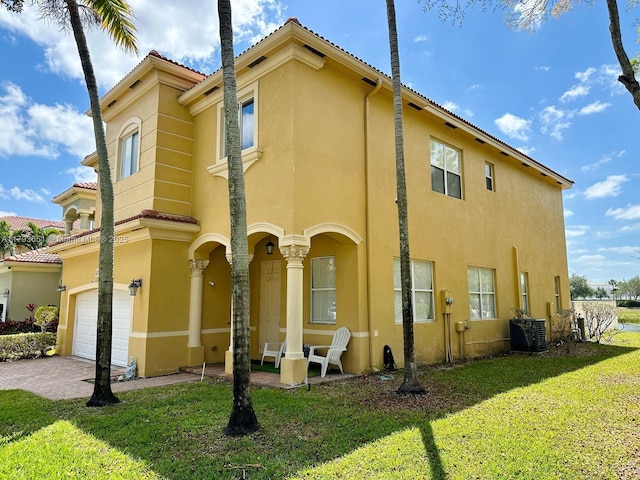 view of side of home featuring stucco siding, a garage, a lawn, and central air condition unit