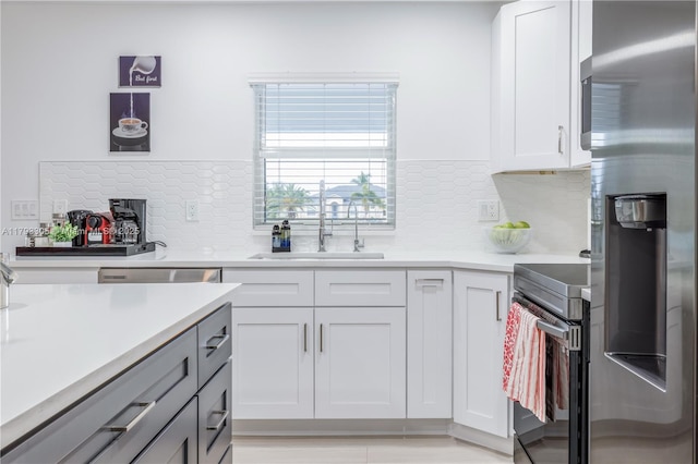 kitchen with decorative backsplash, a sink, light countertops, white cabinets, and stainless steel appliances