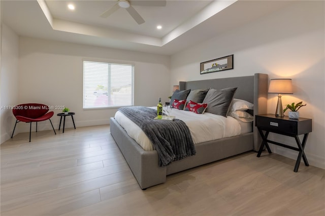 bedroom with ceiling fan, a raised ceiling, recessed lighting, baseboards, and light wood-type flooring