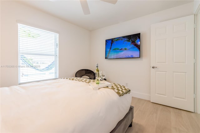 bedroom with baseboards, a ceiling fan, and light wood-style flooring