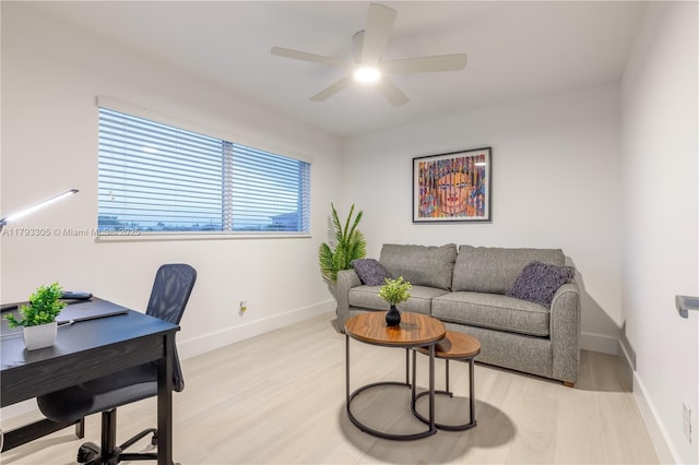 office space featuring baseboards, ceiling fan, and light wood finished floors
