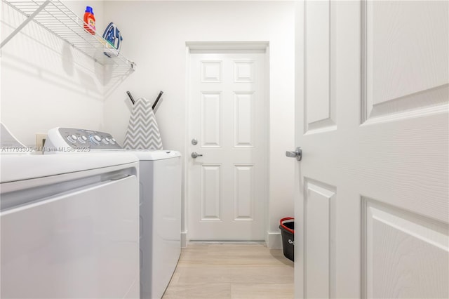 clothes washing area with washer and dryer, laundry area, and light wood-style flooring