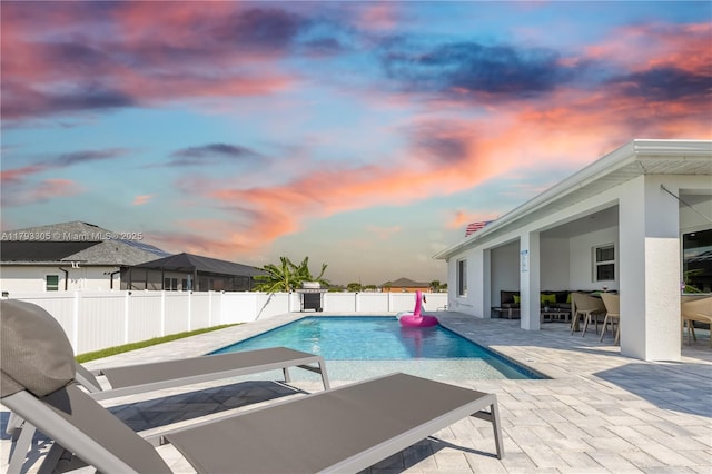 pool at dusk with a patio, a fenced backyard, and a fenced in pool