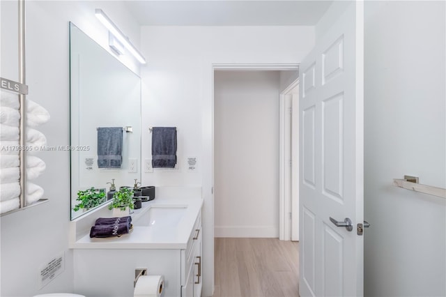 bathroom featuring vanity, baseboards, and wood finished floors