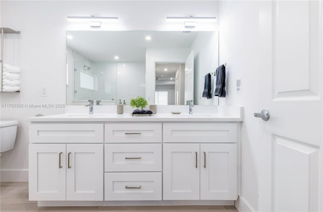 full bathroom with double vanity, a sink, toilet, and a shower stall