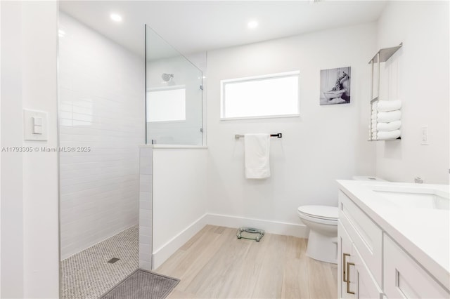 full bathroom with wood finished floors, a walk in shower, baseboards, vanity, and toilet