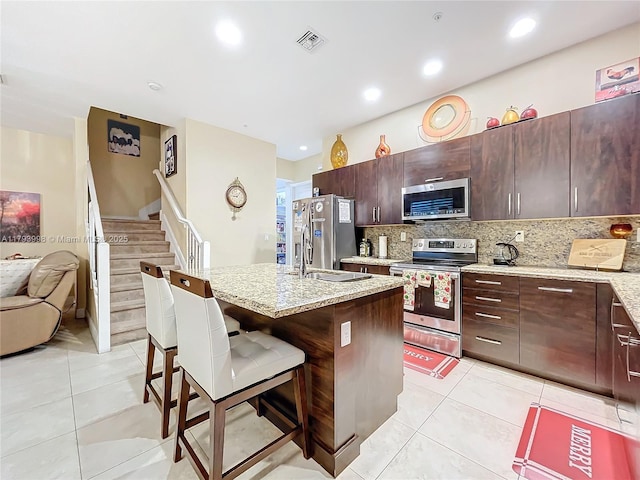 kitchen with visible vents, appliances with stainless steel finishes, light tile patterned floors, and a kitchen bar