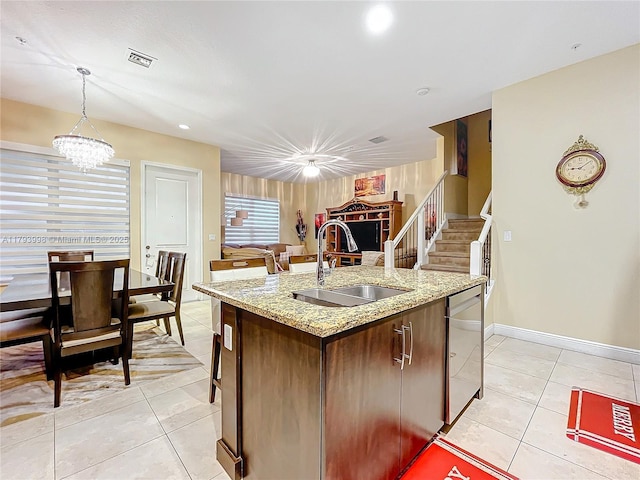 kitchen with visible vents, an island with sink, a sink, light tile patterned floors, and hanging light fixtures