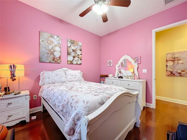 bedroom featuring a ceiling fan, baseboards, visible vents, and wood finished floors