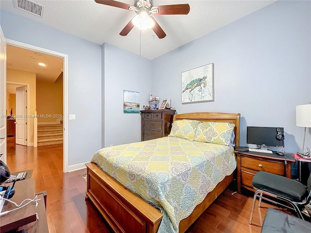 bedroom featuring visible vents, a ceiling fan, baseboards, and wood finished floors