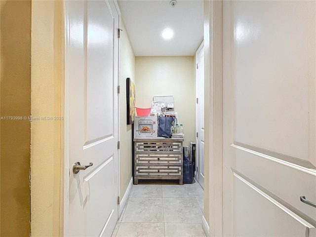 hallway featuring baseboards and light tile patterned floors