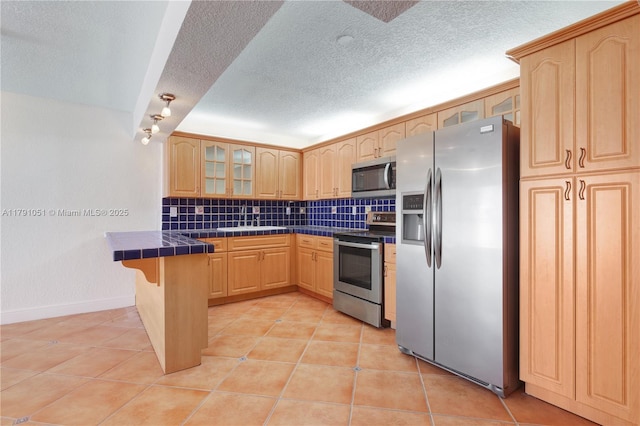 6801 Indian Creek Dr Unit 602, Miami Beach, FL 33141 - kitchen featuring appliances with stainless steel finishes, tile counters, glass insert cabinets, tasteful backsplash, and light tile patterned flooring