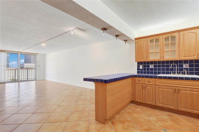 kitchen with a peninsula, a textured ceiling, tile countertops, and rail lighting