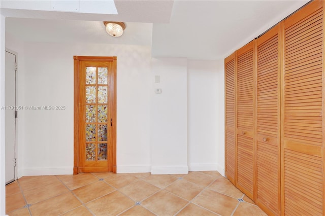 corridor featuring baseboards and light tile patterned floors