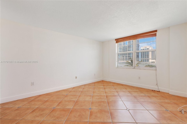 empty room with baseboards and light tile patterned floors
