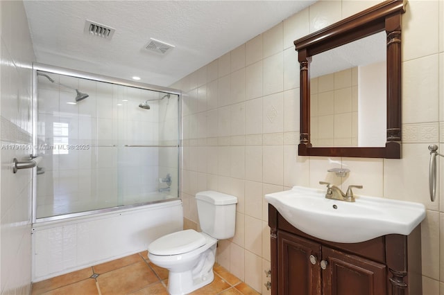 full bath with toilet, tile walls, visible vents, and vanity
