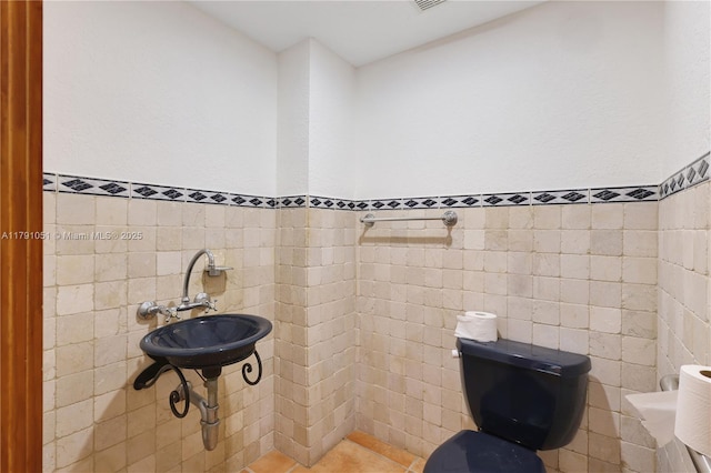 half bath with wainscoting, tile patterned floors, and tile walls