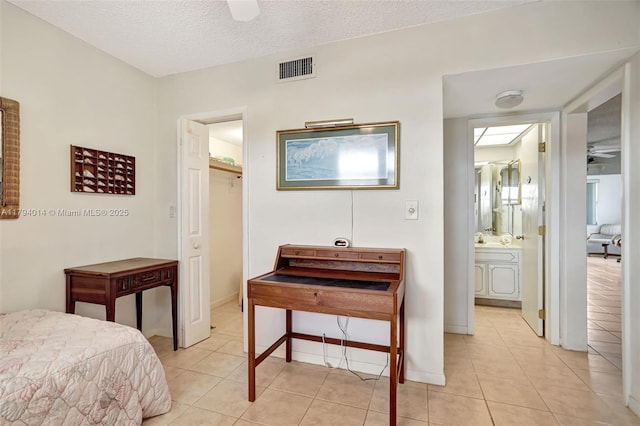 401 S Golf Blvd Unit 270, Pompano Beach, FL 33064 - bedroom featuring light tile patterned floors, a walk in closet, a textured ceiling, and ensuite bathroom