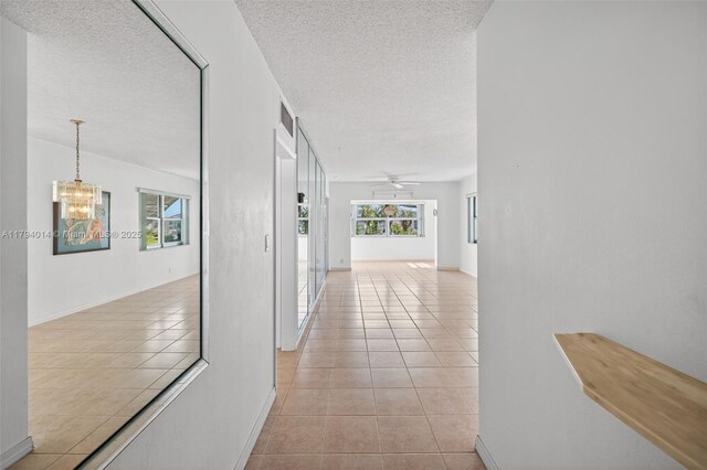 401 S Golf Blvd Unit 270, Pompano Beach, FL 33064 - hallway featuring light tile patterned floors, a textured ceiling, and a chandelier