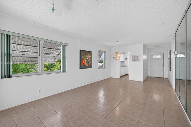 401 S Golf Blvd Unit 270, Pompano Beach, FL 33064 - unfurnished living room featuring tile patterned floors, a textured ceiling, and a chandelier