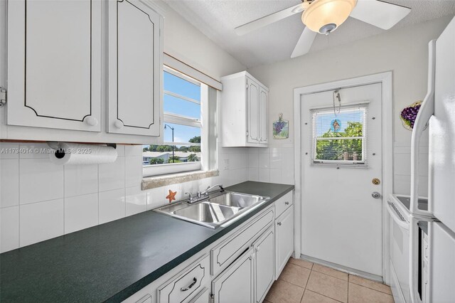 401 S Golf Blvd Unit 270, Pompano Beach, FL 33064 - kitchen featuring dark countertops, healthy amount of natural light, white cabinets, tasteful backsplash, and a textured ceiling